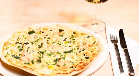 Flammkuchen mit Lauch und Garnelen, dazu ein Glas Weißwein