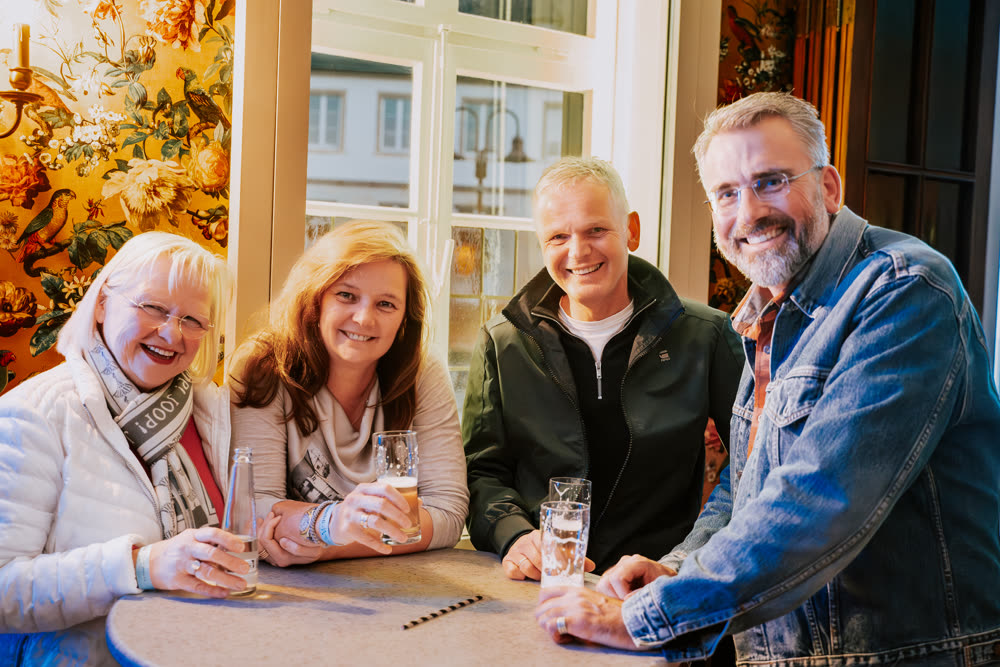 Vier Gäste lachen zusammen an einem Stehtisch
